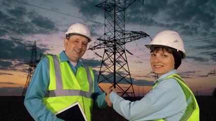 Technician with tablet and inspector shake hand at power distribution substation