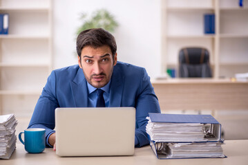 Young male employee and too much work in the office