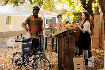 Organic food delivery from local farmers market, young african male courier picking up order at...