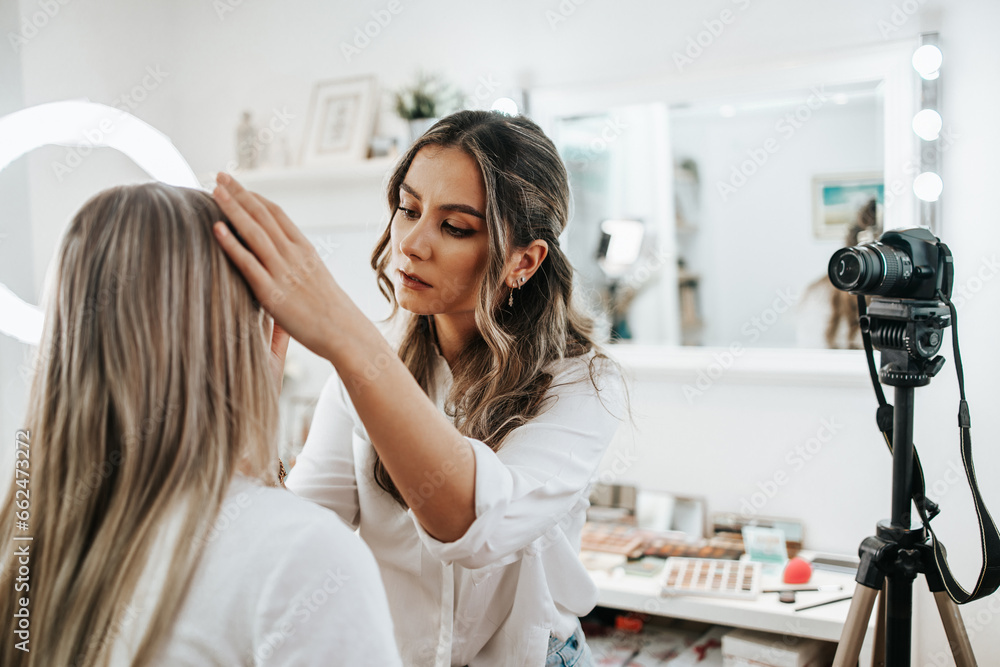 Wall mural happy young woman streaming a beauty makeup vlog from home or workshop. beautiful online content cre