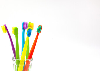 Toothbrushes in a transparent glass on a white background