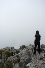 Fototapeta premium Einsamer Wanderer mit Blick nach unten auf Berggipfel bei Nebel