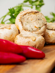 Stuffed mushrooms cups and chilly peppers and garlic cloves on a wooden board and table. High...
