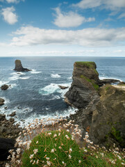 Fototapeta na wymiar Stunning scene with cliffs, rough stone island, ocean and blue cloudy sky. Ireland, Kilkee area. Travel, tourism and sightseeing concept. Irish landscape and coastline. Beautiful nature view.