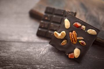 A close-up view of dark chocolate with nuts (cashew, pecan, pistachio) and dried papaya.