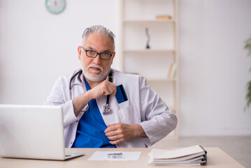 Old male doctor holding credit card