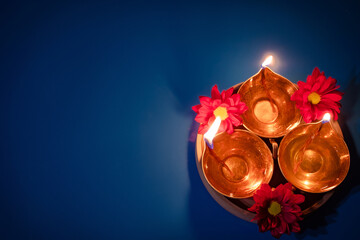 Happy Diwali. Celebrating the Indian Festival of Light. Traditional diya oil lamps and red flowers...