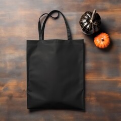 Black tote bag template photo. Black shopper bag lies on brown wooden table with halloween pumpkins. Minimalist product mockup.