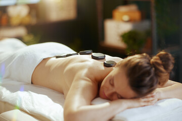 Obraz na płótnie Canvas woman having hot stone massage and laying on massage table