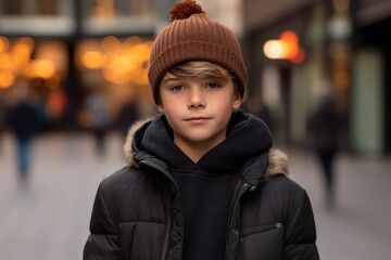 Portrait of a boy in a hat and coat on the street.