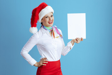 happy female air hostess on blue showing blank a4 paper sheet