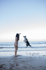 girl and her dog playing on the beach