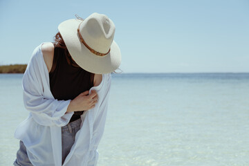 Fototapeta na wymiar unrecognizable fashion model wearing hat on a paradise beach