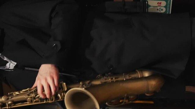 A saxophonist in a suit playing music close up