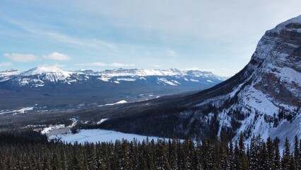 Frozen lake in the Rockies, surrounded by forest during winter, drone view