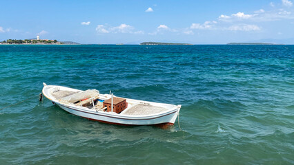 Naklejka premium Boat in the sea on a background of blue sky with clouds