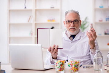 Old male doctor holding book in the clinic