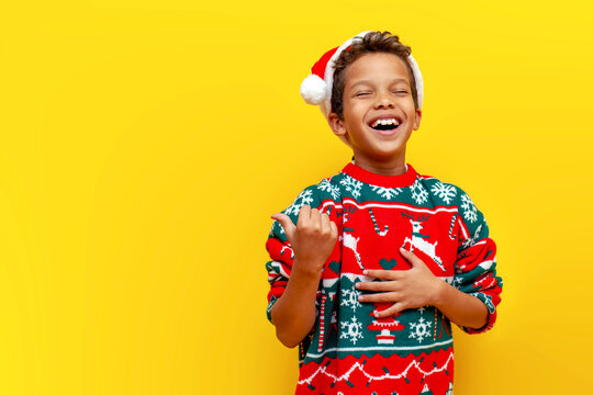 funny african american boy in christmas clothes pointing and advertising empty space and joking and taunting