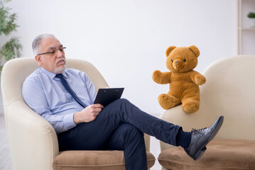 Old male psychologist and soft bear in the room