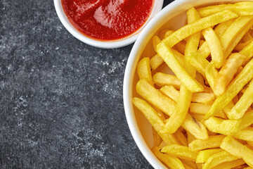 French fries with barbecue sauce, in a white bowl, dark background with place for text