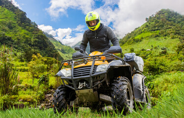 Man on quad bike. Guy drives off-road. Extreme race on quad bike. ATV driver in helmet. Man with ATV in picturesque place. Quadcyclist overcoming off-road conditions. ATV for outdoor activities