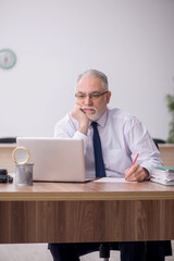 Fototapeta premium Old male employee working in the office