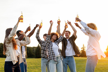 group of multiracial friends at party with bottles of beer dancing and having fun outdoors, group of people singing