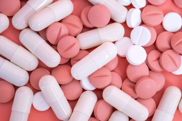 Many pink and white pills and capsules. Medical treatment with medicine, vitamins or nutrition...