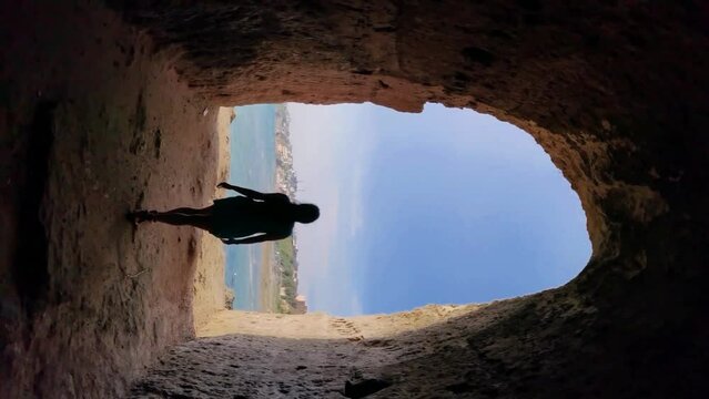 Vertical video of a girl walking in the cave with Anzio sea out