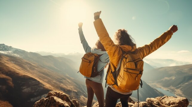 Exhilarated friends, reaching a mountain peak, arms triumphantly thrown in the air, celebrating the victorious hike.