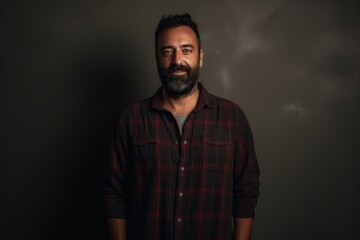 Portrait of a bearded man in a plaid shirt on a dark background