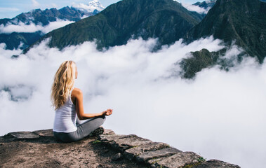Naklejka na ściany i meble female traveler enjoying beauty of Machu Picchu landscape and high mountains covered clouds