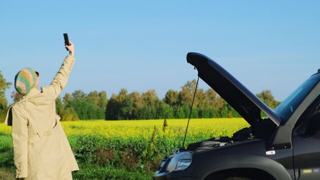 Hysterical woman on countryside road trying to get help to her broken down car. Female driver having a problem, she looking for a cellular network signal while bad mobile network coverage.