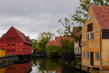 Outdoor overcast scenery of canal surrounded with old traditional wooden houses at Den Gamle By in Aarhus, Denmark. 