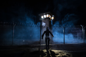 Old prison watchtower protected by wire of prison fence at night. Creative art decoration. Selective focus