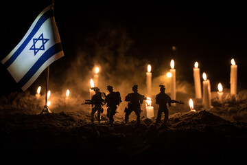 Israel flag on burning dark background with candle. Attack on Israel, mourning for victims concept...