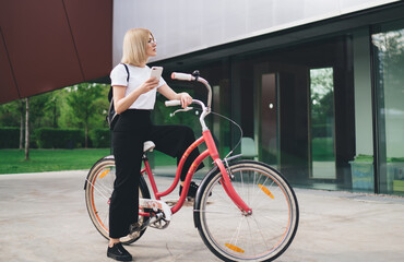 Fototapeta premium Female browsing smartphone on bicycle near mall