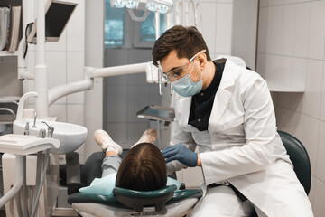 People, medicine, stomatology, technology and health care concept. Male dentist working with girl in clinic.