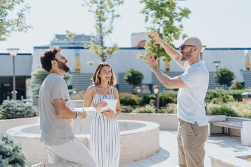 Architects discuss blueprint outdoors, analyzing statistics and solving problems for a construction project. Successful teamwork ensures modern infrastructure and efficient site planning in the city.