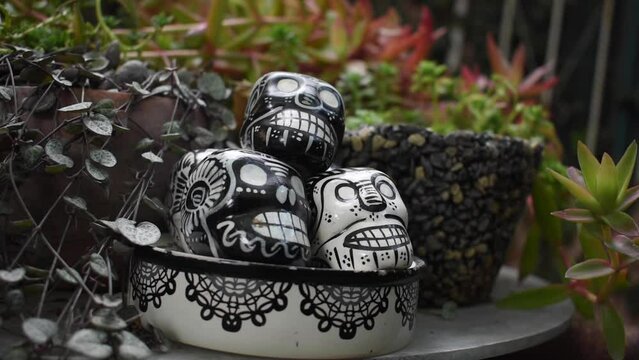 Calaveras de Talavera en un jardín con el fondo de macetas jardinería y tradiciones en Mexico para el 2 de octubre 