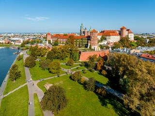 Krakow, Poland. Royal Wawel castle and cathedral, public parks, promenades and boulevards along Vistula river. Walking people and small harbor with tourist boats.  Aerial view in autumn