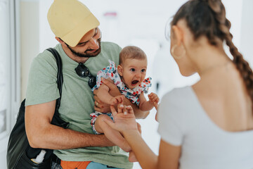 Father and little baby daughter waiting for their turn at the hospital. Baby girl playing with random female patient at the hospital.