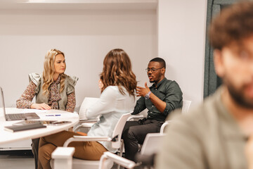 Different aged, diverse group of creative people learning, sharing knowledge and ideas together, brainstorming at modern classroom.