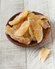 Candied ginger in a plate on a white wooden background. candied fruits