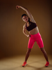 Muscular woman stretching her spine before working out in studio