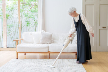 リビングを掃除するシニア女性