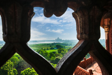 Overlooking the Taj Mahal and Yamuna River from the windows of the Red Fort. Agra Fort is a historic red sandstone fort and a UNESCO World Heritage Site.