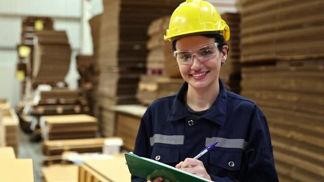 Portrait worker professional young beautiful woman warehouse worker checking goods inside the warehouse cardboard manufacturing factory product packaging logistics working taking notes in clipboard. 
