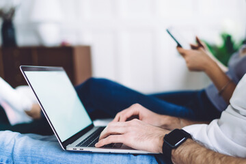 Adult man working at laptop while sitting near woman
