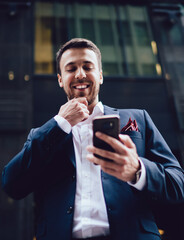 Cheerful boss using smartphone in downtown